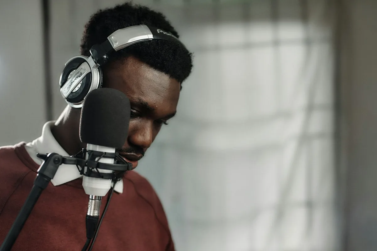 A recording artist wearing headphones at a studio microphone